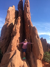 Director of Community and Public Relations Jan Arrant climbs a rock in exercise clothes.