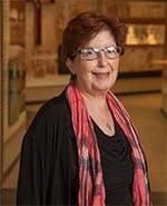 Woman in hospital hall wearing scarf and smiling at the camera