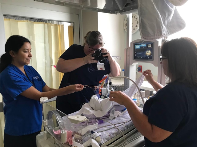 Nurses take photos of NICU babies in crochet hats.
