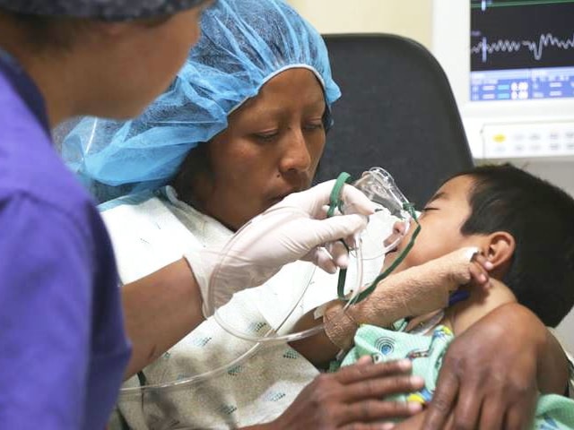 Woman cuddles a small boy in a hospital room during a Methodist surgical medical mission trip.