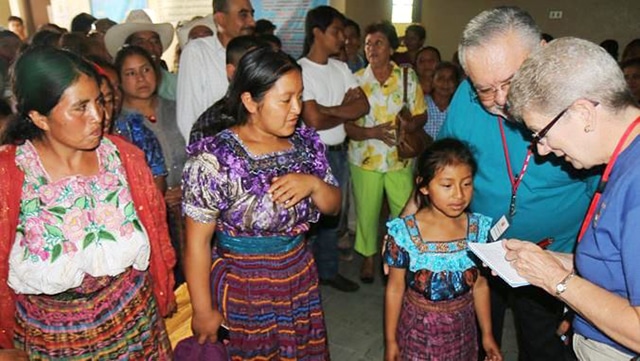 Two women and a young girl speak to volunteers for their health screenings during a surgical medical mission trip. 