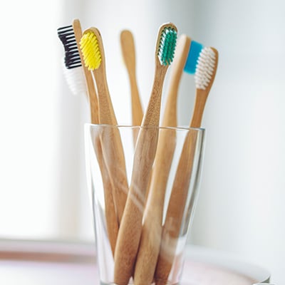 six toothbrushes resting in glass cup on countertop